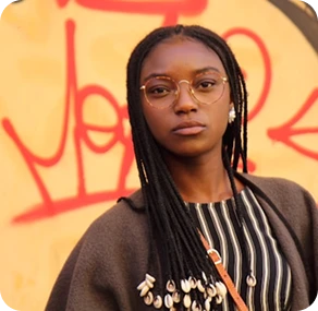 Young woman by a graffiti-covered wall.